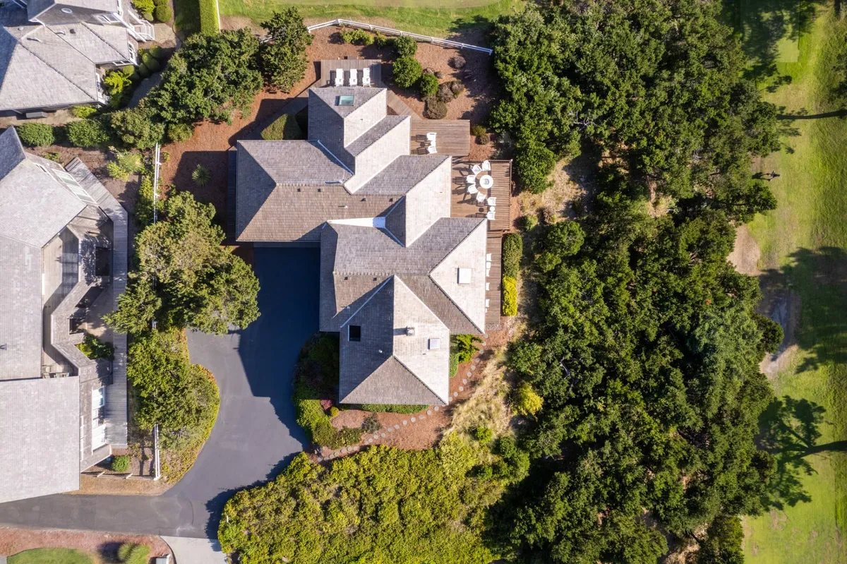 A spacious residential home with a sweeping patio area, surrounded by lush greenery. In the background, the well-maintained expanse of a golf course is visible, emphasizing the home's direct proximity to the greens. The patio is inviting, ideal for relaxing outdoors or entertaining guests while enjoying uninterrupted views of the course.