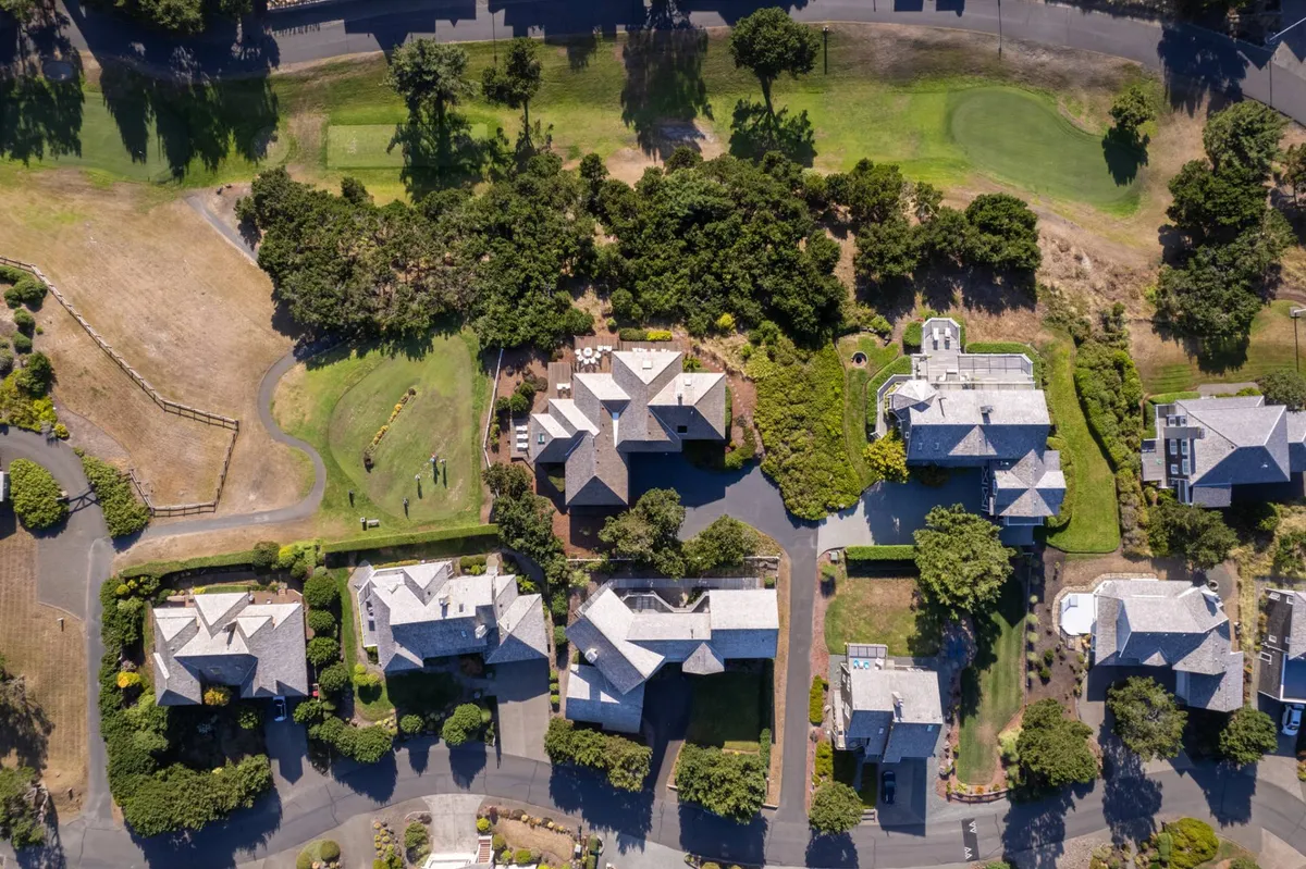 A tranquil streetscape featuring neatly arranged houses, abundant lush greenery, and gently winding roads. The landscape evokes the exclusivity and calm of a private, gated community, where privacy and connection to nature are seamlessly integrated.