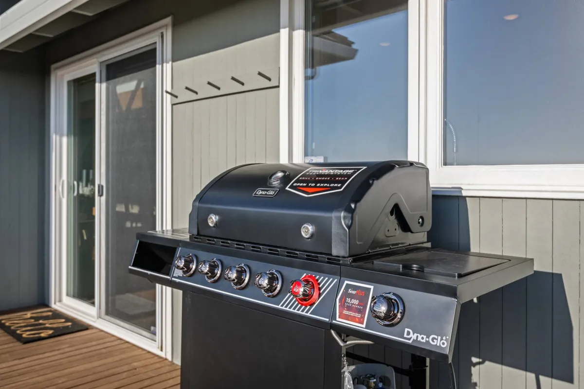 An inviting deck accessed via sliding glass doors, featuring a grill and spacious seating area—ideal for outdoor dining and socializing just steps from the kitchen.