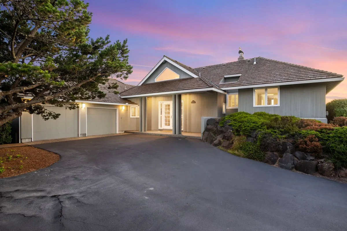 This image displays the front entrance of High Ridge House, framed by well-maintained landscaped bushes and a spacious driveway. The porch area hints at opportunities for outdoor gatherings or enjoying the evening air, establishing an immediate sense of arrival and setting the tone for exploring the surrounding coastal towns.