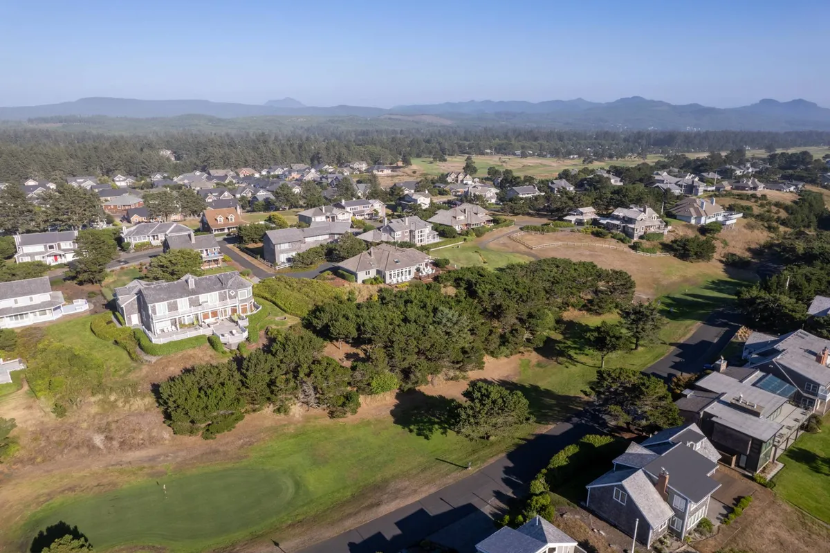 A wide-angle view of the neighborhood, highlighting a beautifully integrated golf course winding through tree-lined streets and well-spaced homes. The scene conveys a sense of peaceful community living with easy access to golf and green spaces.